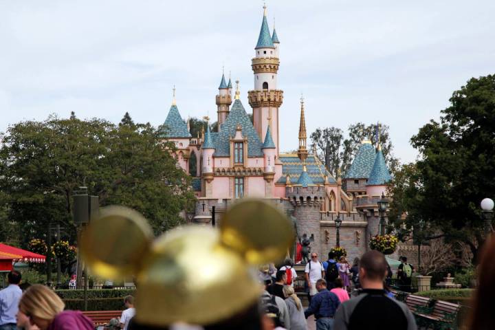 In this file photo, visitors walk toward the Sleeping Beauty's Castle in the background at Disn ...