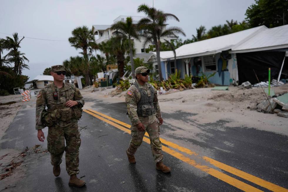 Members of the Florida Army National Guard walk past a home slated for demolition after being d ...