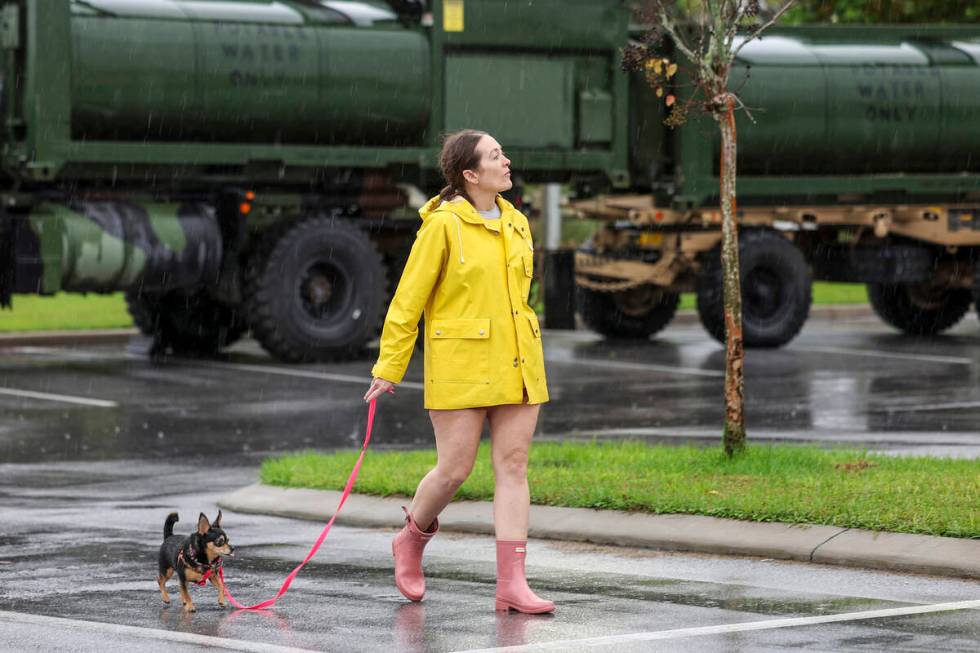 Erin Ferguson walks her dog while looking at equipment stationed by the Florida National Guard ...