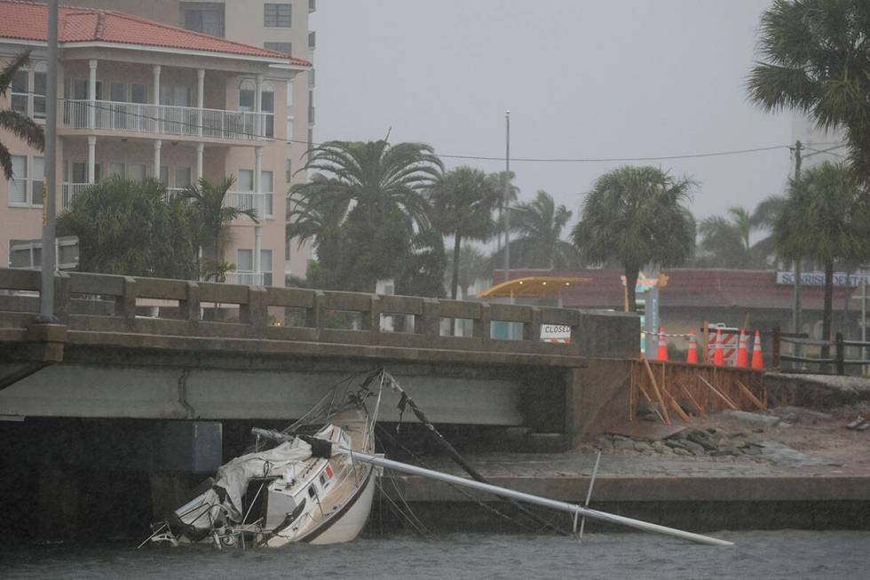 A boat damaged in Hurricane Helene rests against a bridge ahead of the arrival of Hurricane Mil ...