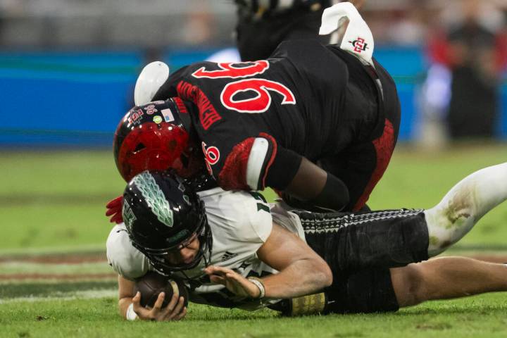 San Diego State defensive end Ryan Henderson, top, runs into Hawaii quarterback Brayden Schager ...