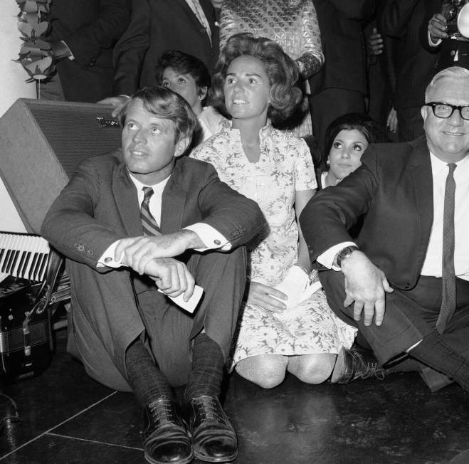 Sitting on the floor and surrounded by party-goers, Sen. Robert F. Kennedy (D-NY), looks on at ...