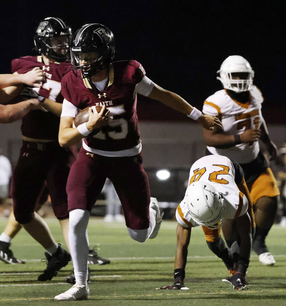 Faith Lutheran's quarterback Alexander Rogers (15) avoids a tackle from Legacy High's linebacke ...