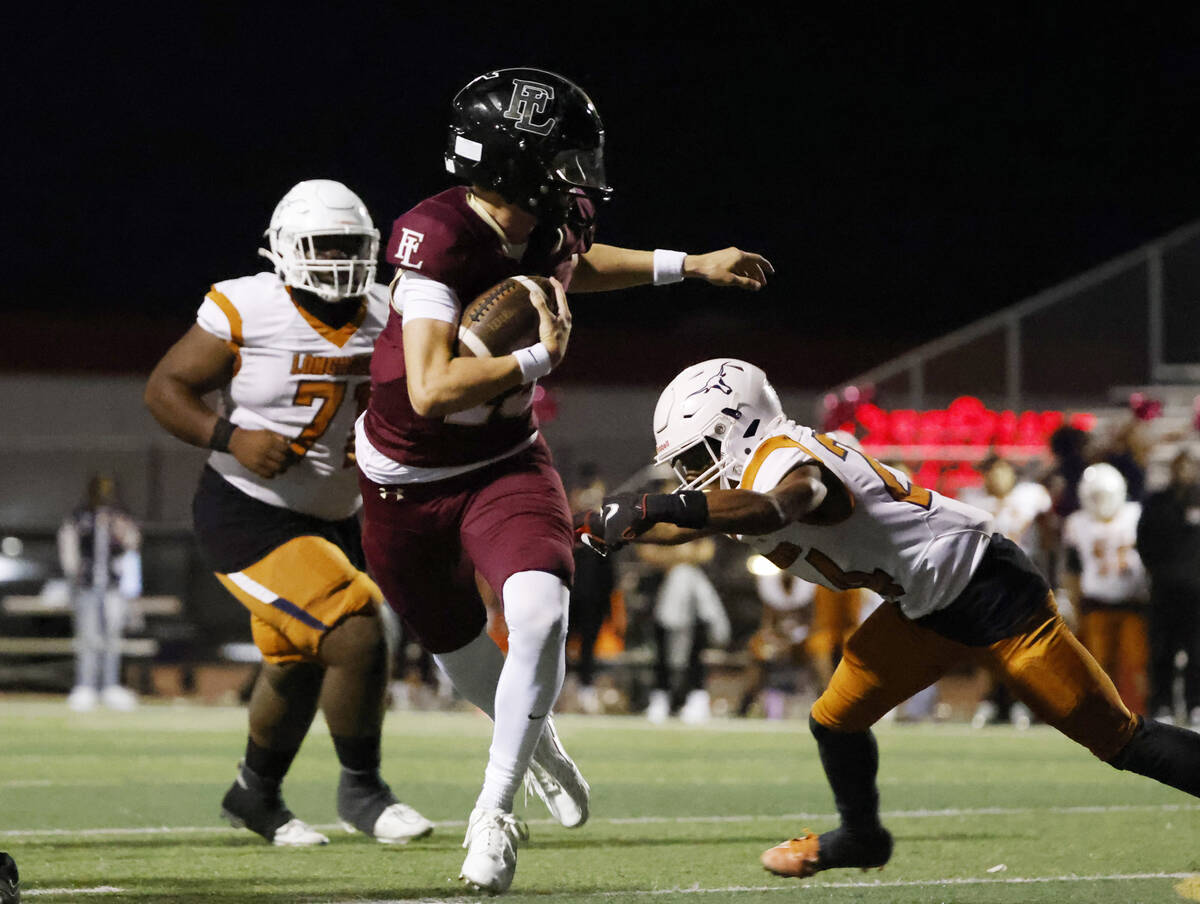 Faith Lutheran's quarterback Alexander Rogers (15) avoids a tackle from Legacy High's linebacke ...