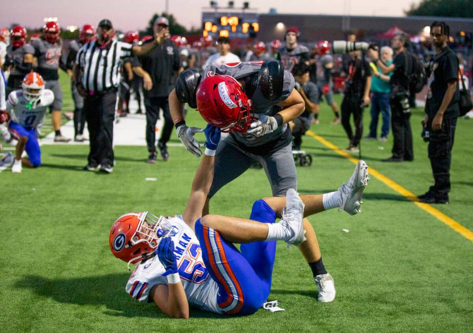 Bishop Gorman linebacker Brodey Correa (52) holds on to the helmet of Arbor View linebacker Roc ...