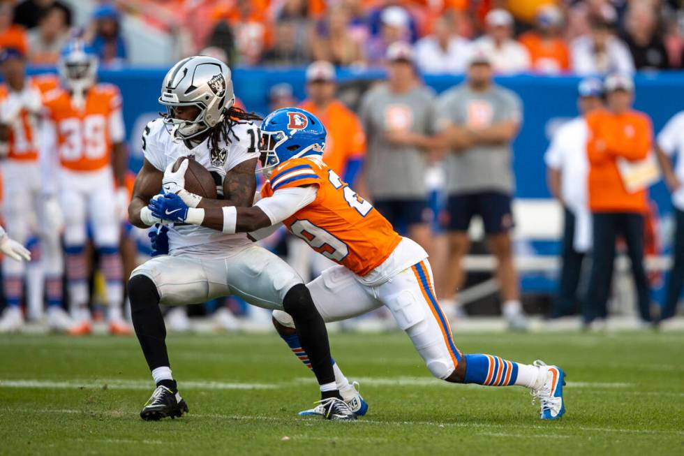 Raiders wide receiver Jakobi Meyers (16) makes a catch with Denver Broncos cornerback Ja'Quan M ...