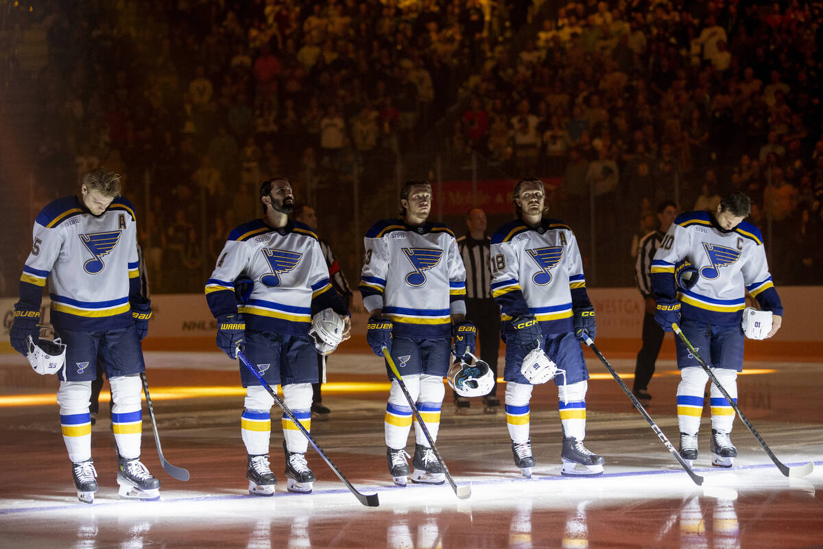 The St. Louis Blues starting lineup stands on the ice for the national anthem during the NHL ho ...