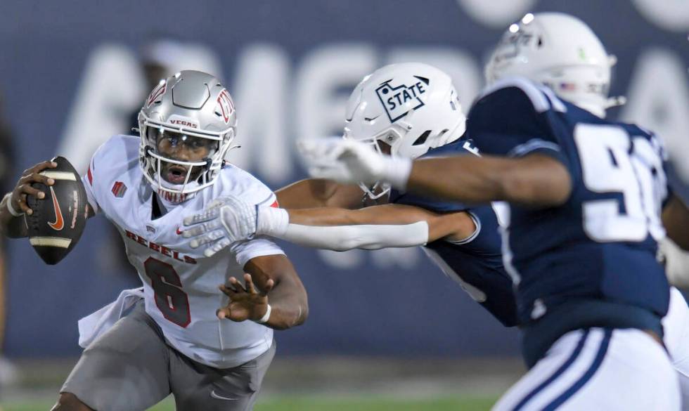 UNLV quarterback Hajj-Malik Williams (6) scrambles away from Utah State defensive end Lawrence ...