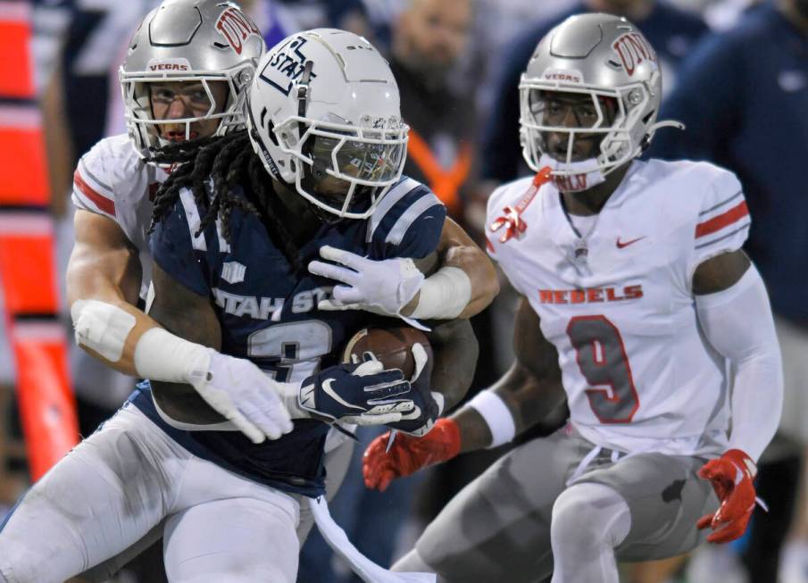 UNLV linebacker Jackson Woodard, back left, tackles Utah State running back Rahsul Faison (3) a ...