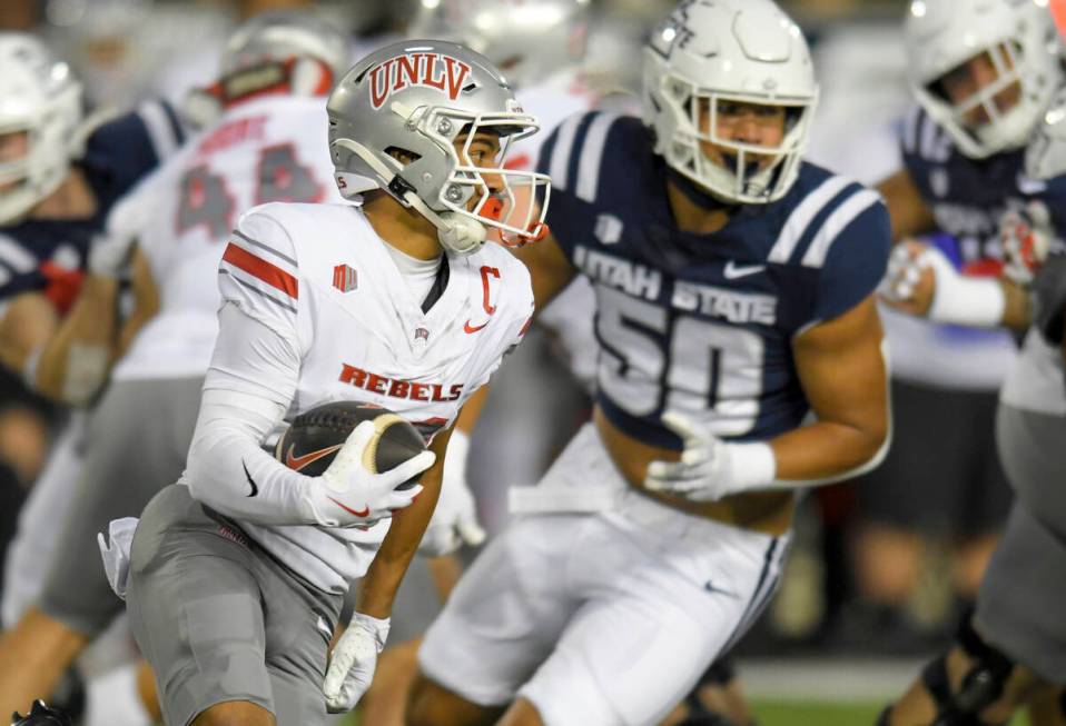 UNLV wide receiver Jacob De Jesus, left, carries the ball as Utah State defensive end Lawrence ...