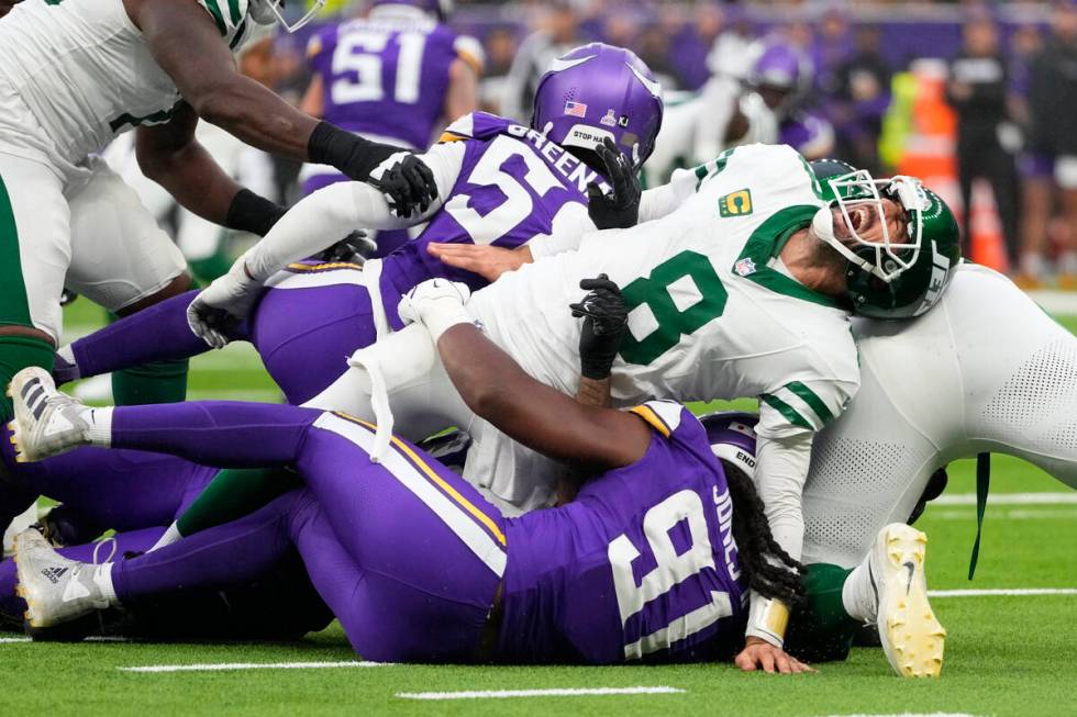 New York Jets quarterback Aaron Rodgers (8), right, reacts as he is tackled during the second h ...