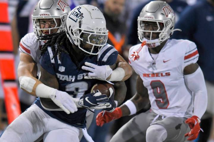 UNLV linebacker Jackson Woodard, back left, tackles Utah State running back Rahsul Faison (3) a ...