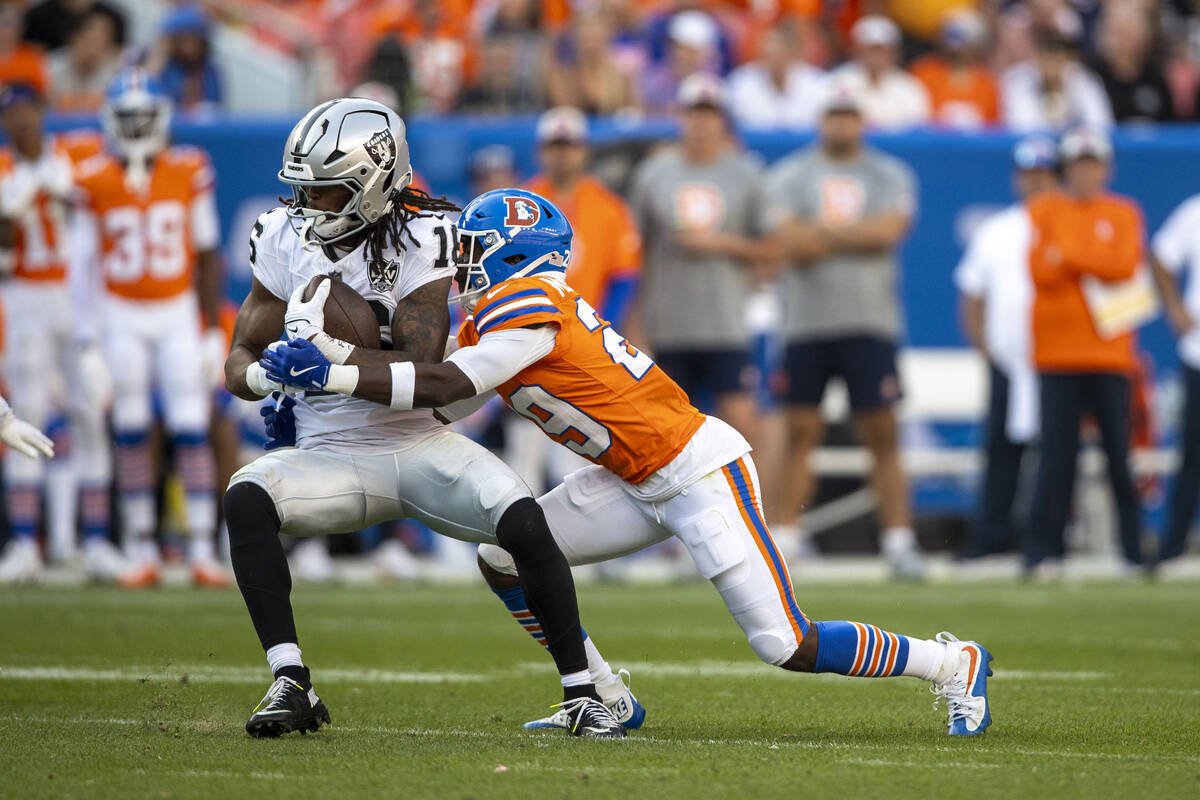 Raiders wide receiver Jakobi Meyers (16) makes a catch with Denver Broncos cornerback Ja'Quan M ...