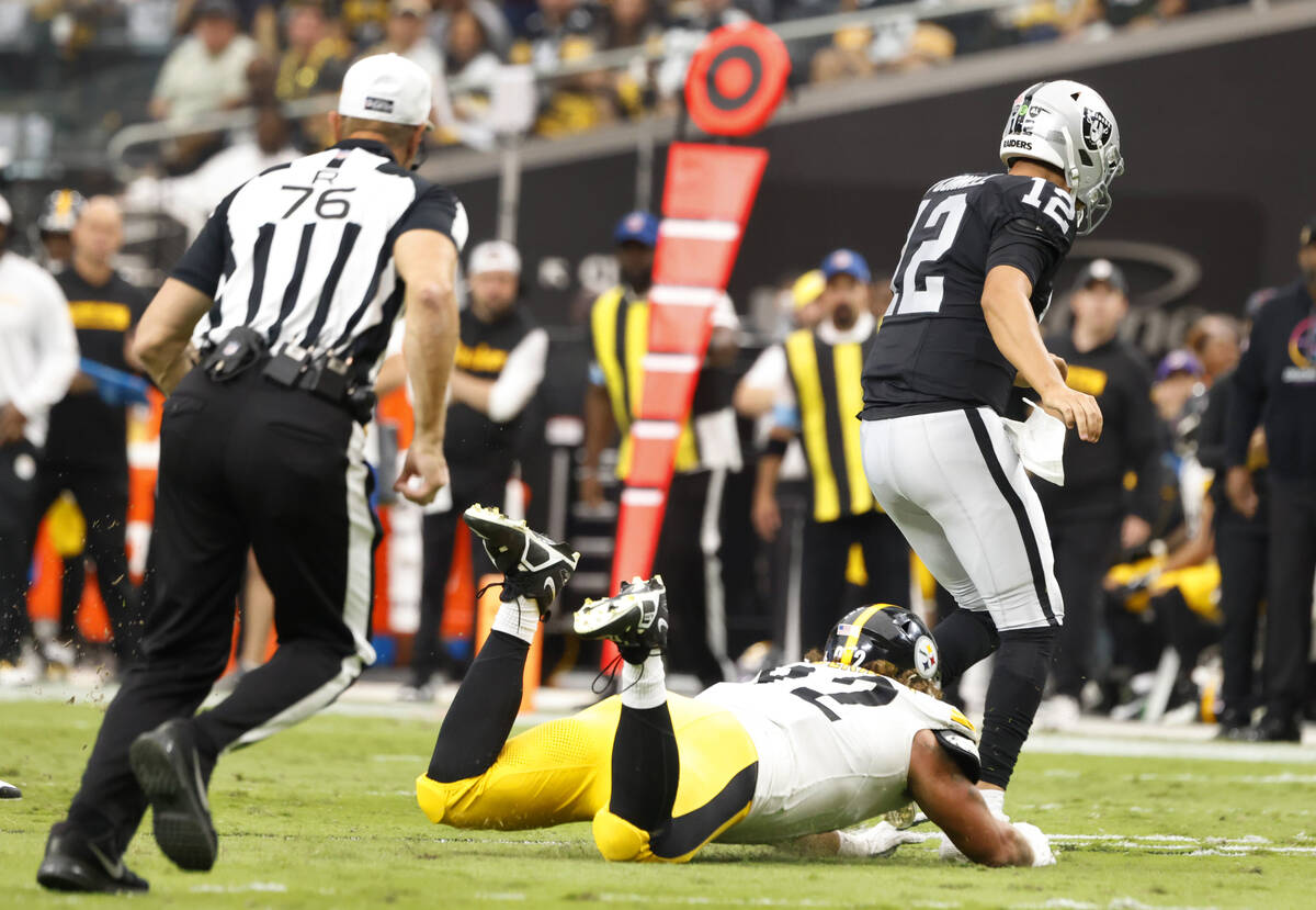 Raiders quarterback Aidan O'Connell (12) is tripped by Pittsburgh Steelers defensive tackle Isa ...