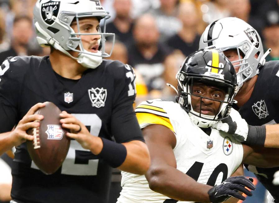 Raiders quarterback Aidan O'Connell (12) throws under pressure from Pittsburgh Steelers linebac ...