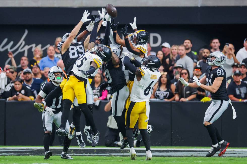 Raiders and Pittsburgh Steelers players reach for the ball from a pass by Raiders quarterback A ...