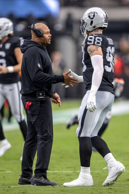 Raiders head coach Antonio Pierce speaks with defensive end Maxx Crosby (98) during the first h ...