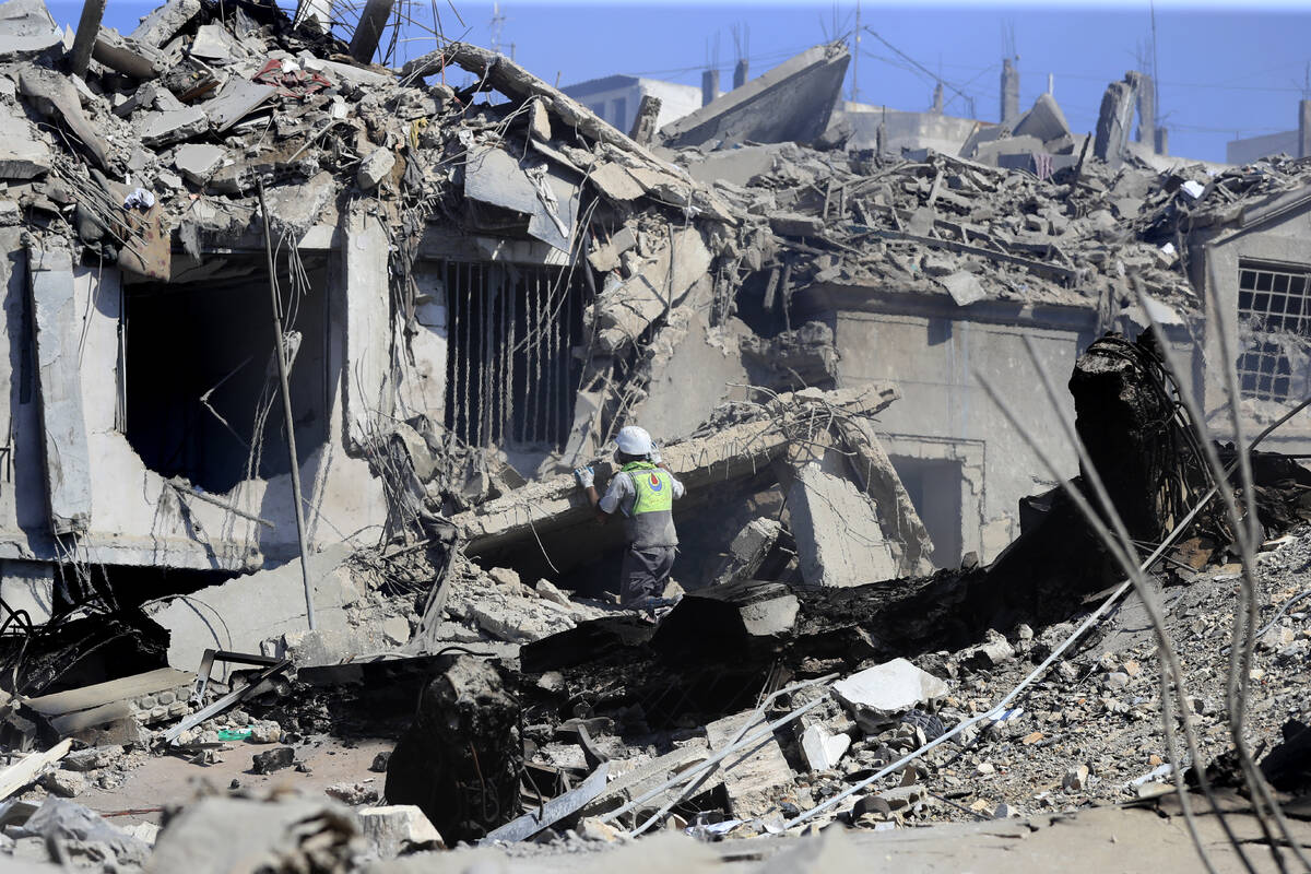 A Hezbollah rescue worker searches for victims amidst the rubble of destroyed buildings at a co ...