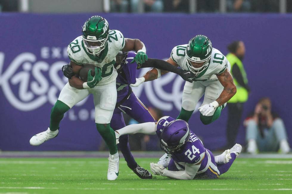 New York Jets' Breece Hall (20), left, runs the ball during the second half of an NFL football ...