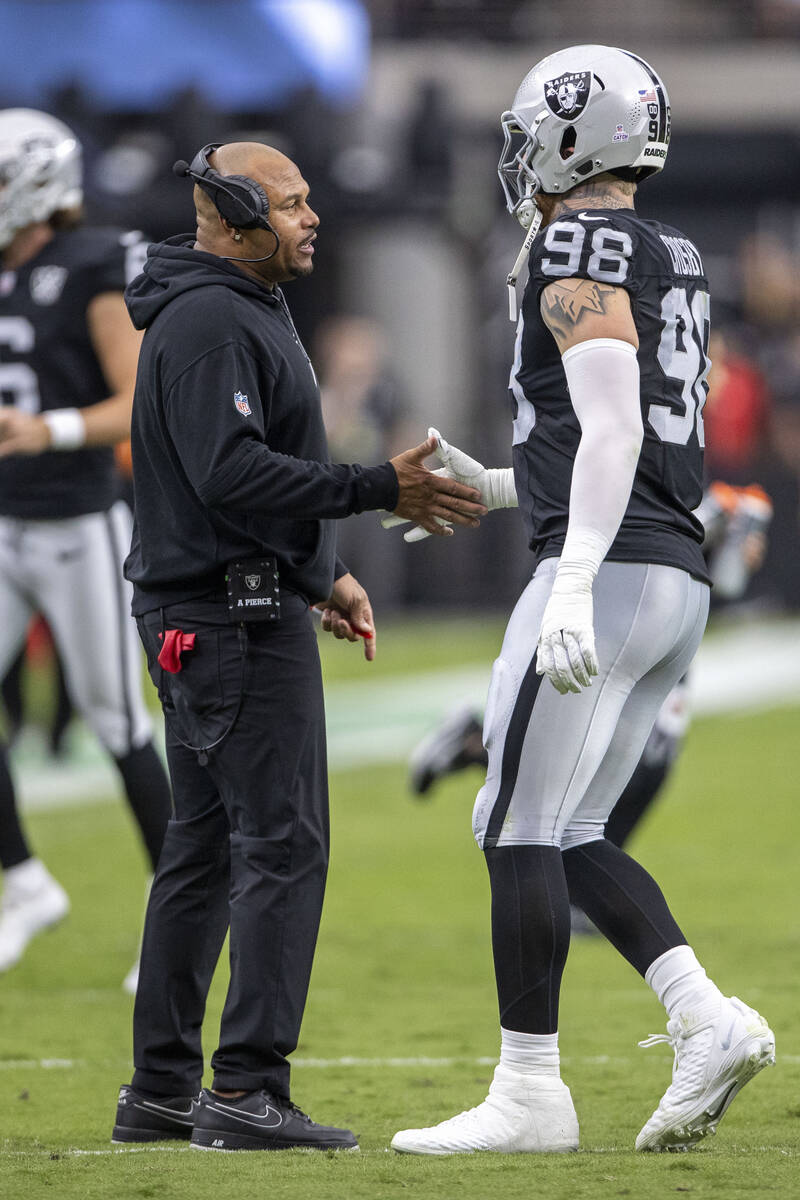 Raiders head coach Antonio Pierce speaks with defensive end Maxx Crosby (98) during the first h ...