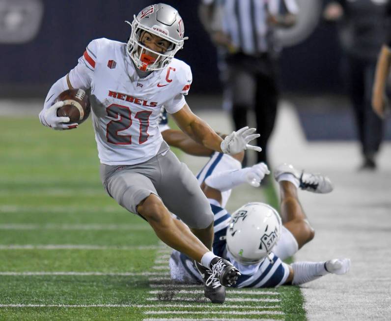 UNLV's Jacob De Jesus (21) runs past Utah State's Otto Tia, bottom right, as he returns a punt ...