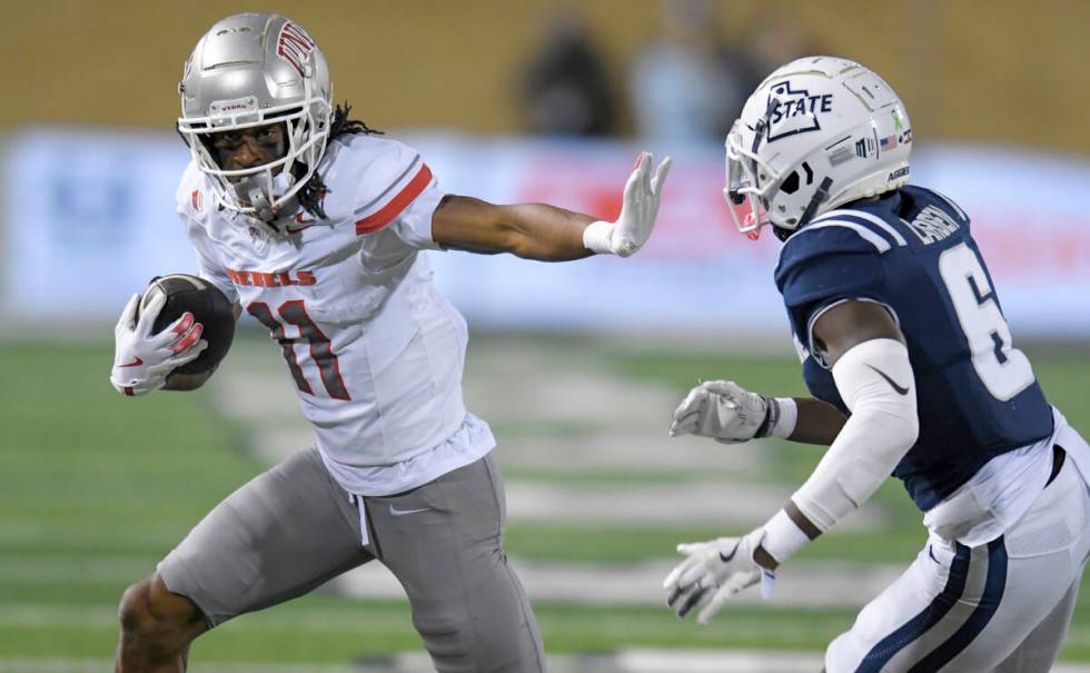 UNLV wide receiver Ricky White III (11) runs downfield as Utah State safety Ike Larsen (6) defe ...