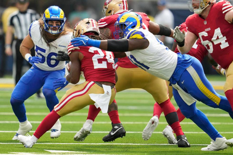 Los Angeles Rams defensive tackle Kobie Turner, right, reaches to tackle San Francisco 49ers ru ...