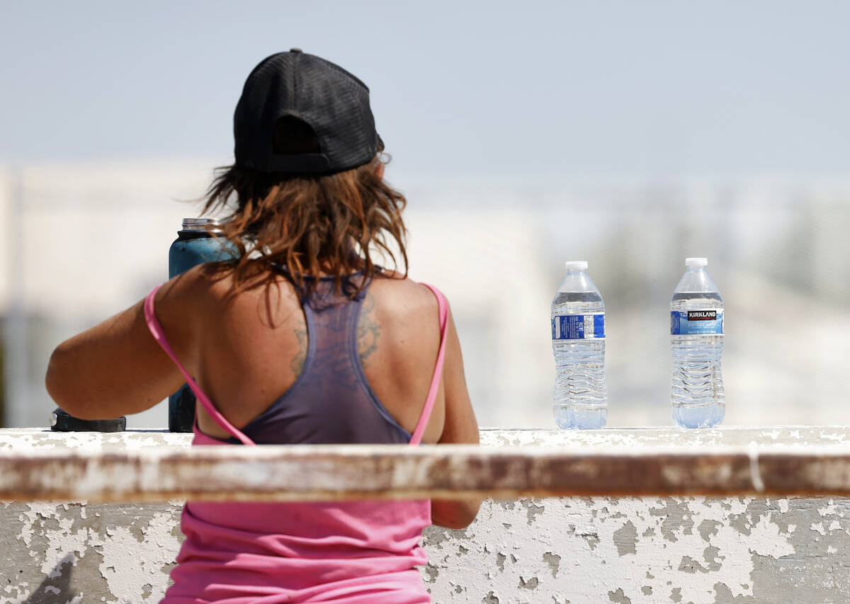 A homeless person fills up her water bottle, delivered by a Help of Southern Nevada outreach wo ...