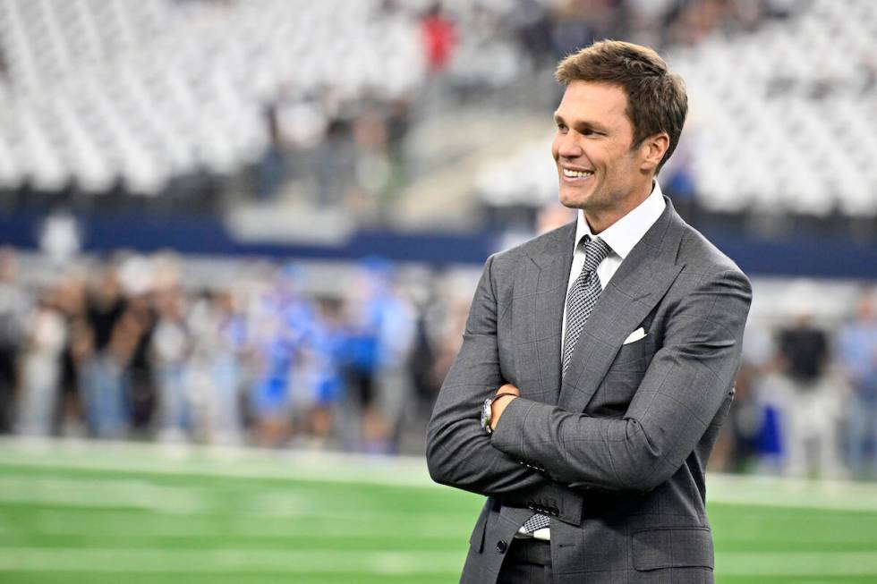 Analyst Tom Brady stands on the field during warmups before first an NFL football game between ...