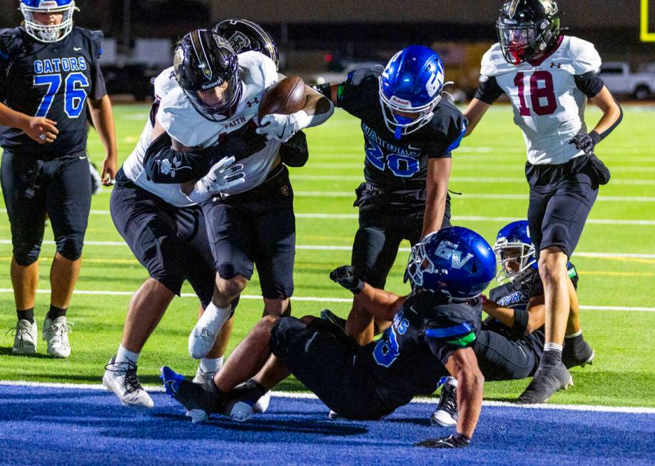 Faith Lutheran running back Cale Breslin (14) scores as Green Valley defensive end Nash Wilkins ...