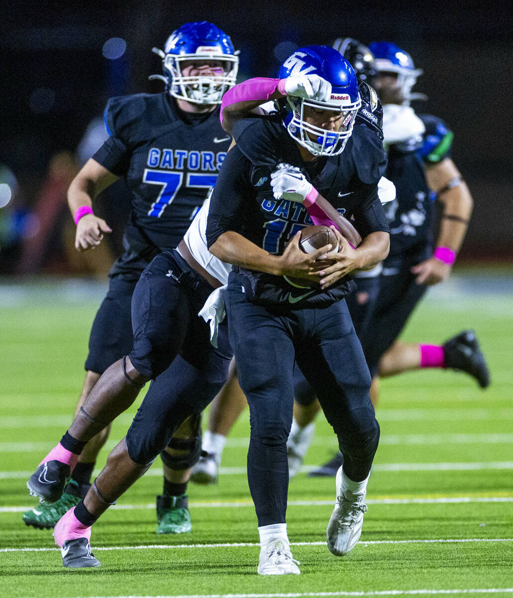 Green Valley quarterback Michael Lewis (15) is sacked by Faith Lutheran linebacker Ricky Manni ...