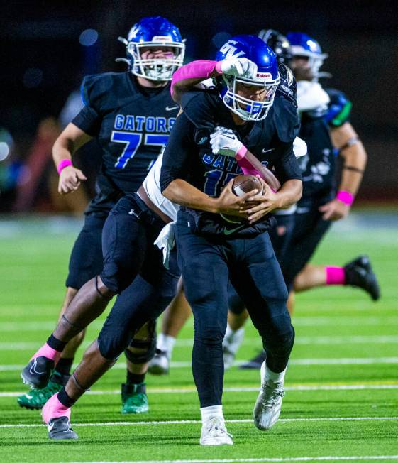 Green Valley quarterback Michael Lewis (15) is sacked by Faith Lutheran linebacker Ricky Manni ...