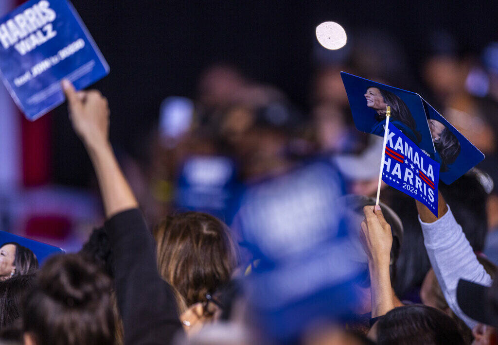 The crowd holds up signs and flags as Former President Barack Obama speaks on behalf of the Har ...