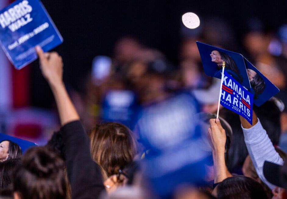 The crowd holds up signs and flags as Former President Barack Obama speaks on behalf of the Har ...