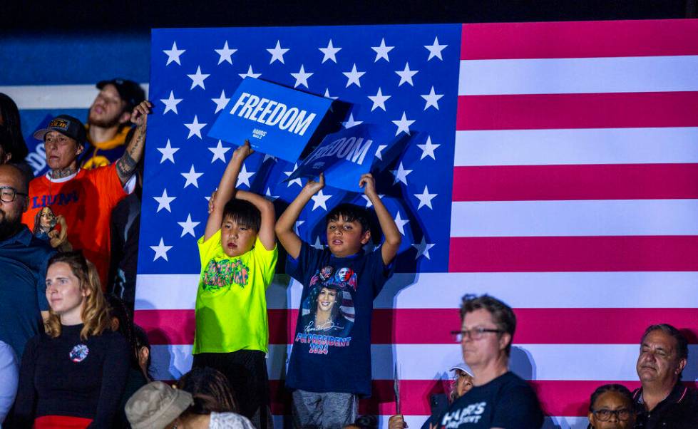 Youngsters hold up signs as Former President Barack Obama speaks on behalf of the Harris-Walz c ...