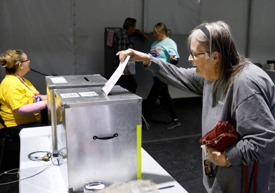 Jean Debarre drops her ballots in an official mail-in ballot drop box during early voting at Th ...