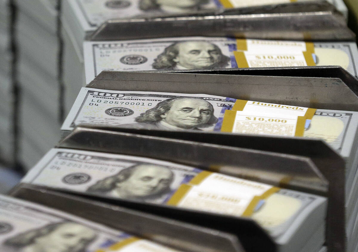 FILE - Cut stacks of $100 bills make their way down the line at the Bureau of Engraving and Pri ...