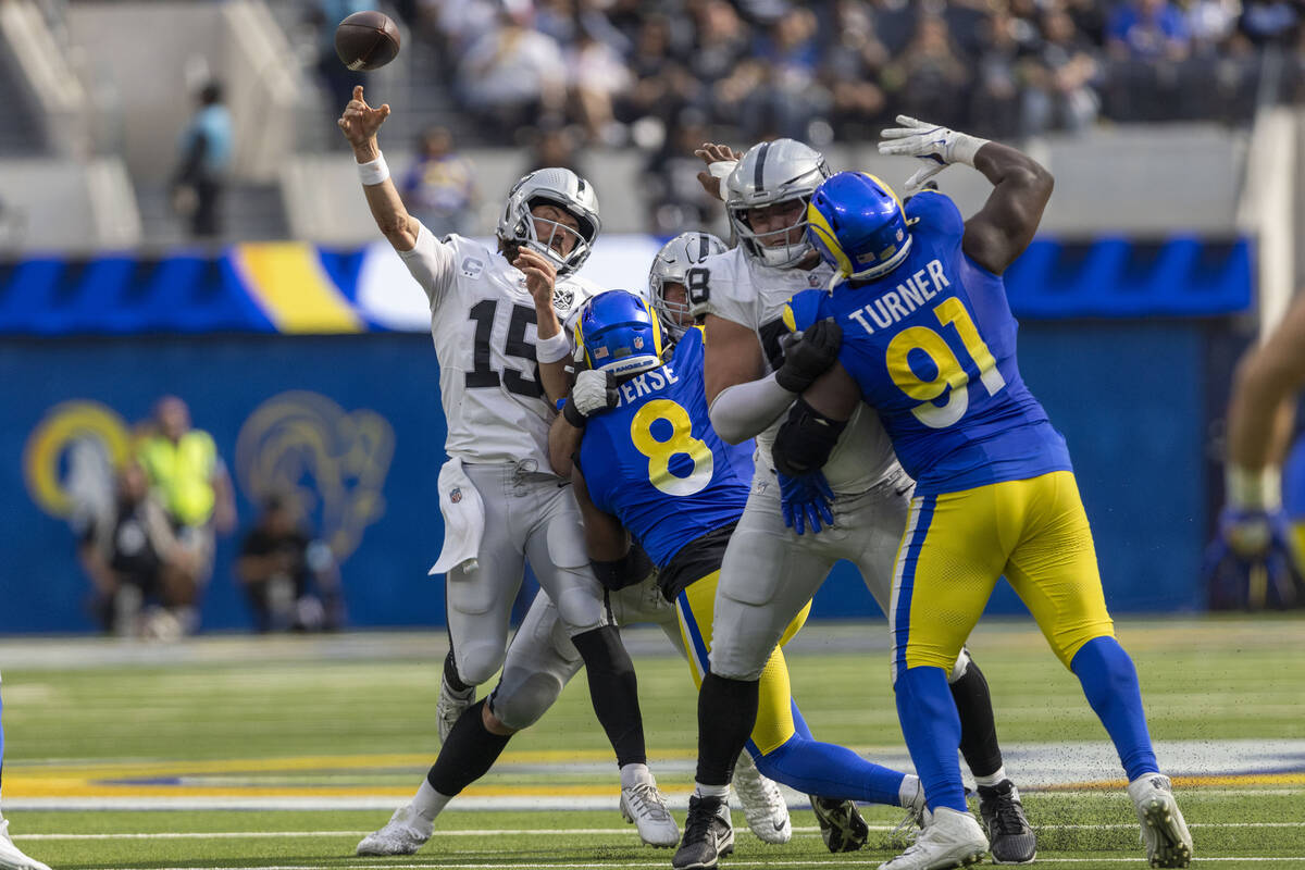 Raiders quarterback Gardner Minshew (15) is hit by Los Angeles Rams linebacker Jared Verse (8) ...