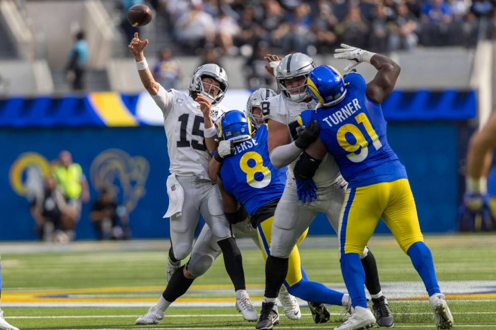 Raiders quarterback Gardner Minshew (15) is hit by Los Angeles Rams linebacker Jared Verse (8) ...