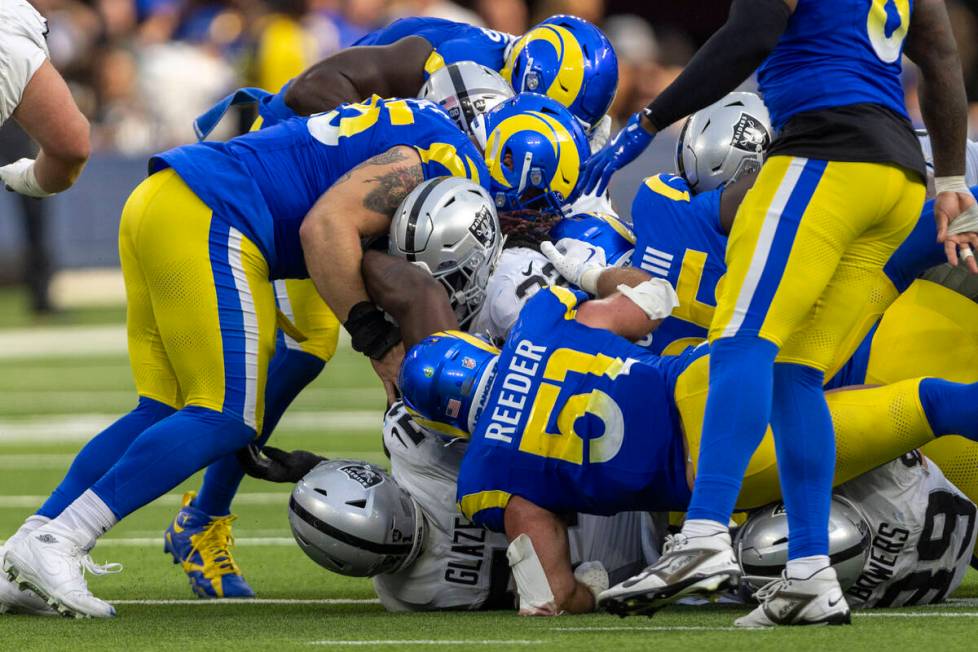 Raiders running back Alexander Mattison (22) squeezes past several Los Angeles Rams defenders i ...