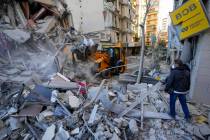 Rescue workers use a bulldozer to remove rubble of destroyed buildings at the site of an Israel ...