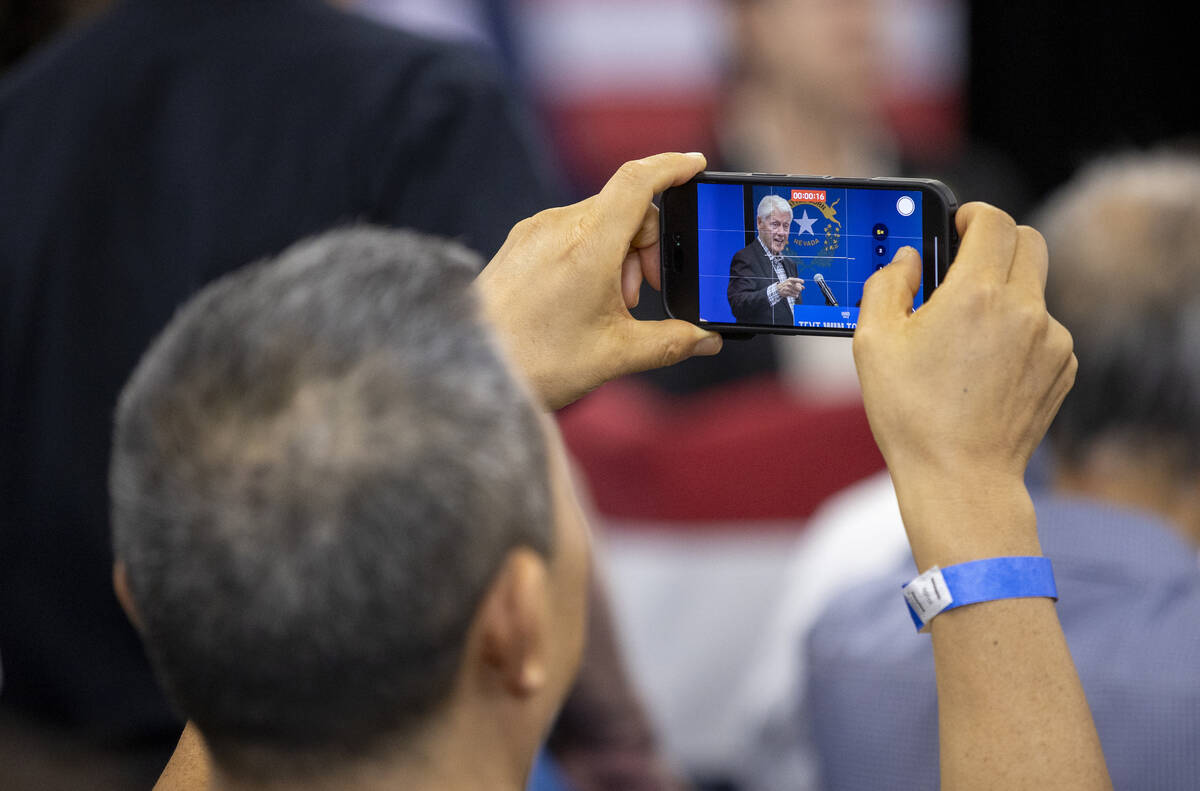 An attendee films former President Bill Clinton speak during a Harris-Walz campaign stop at the ...