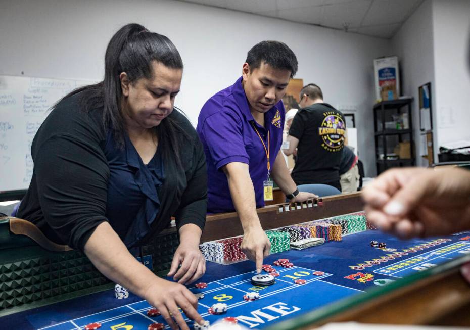 Michelle Robson, left, gets help from Alex Kim, executive director of Casino Education Group, a ...