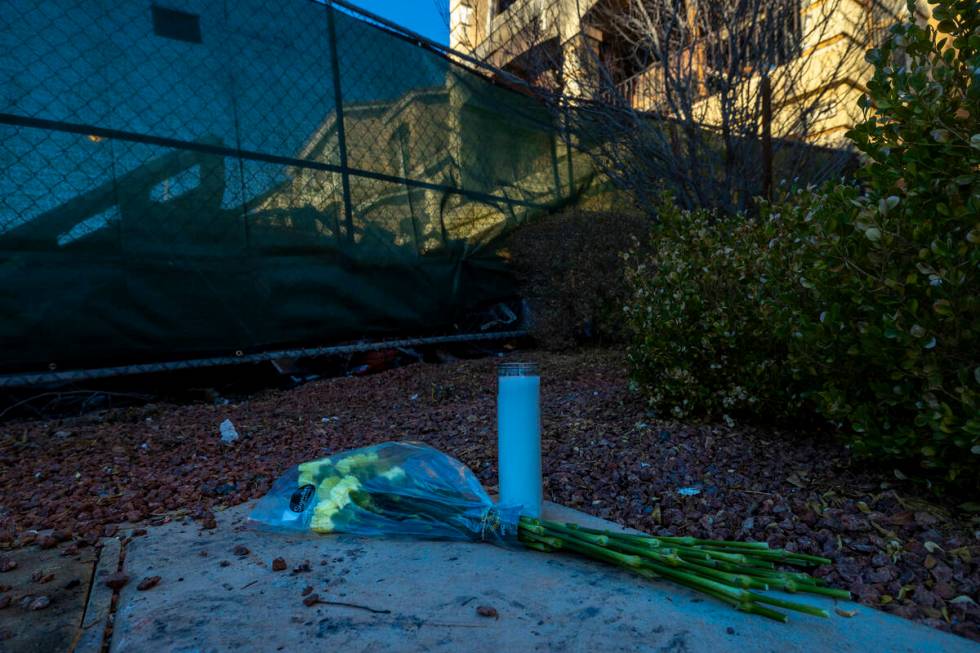 Flowers and a candle left near emergency fencing about the exterior of fatal house fire at 8332 ...