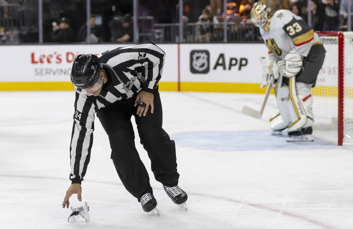 A referee picks up a shoe guard during the NHL hockey game between the Ottawa Senators and Vega ...