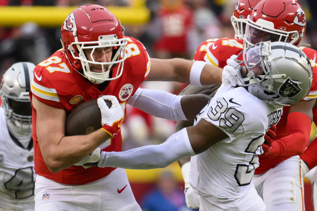 Kansas City Chiefs tight end Travis Kelce (87) fights off a tackle by Las Vegas Raiders cornerb ...