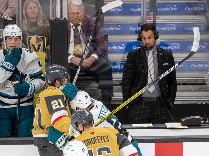 Color commentator Shane Hnidy reacts as sticks fly nearby while reporting between the team benc ...