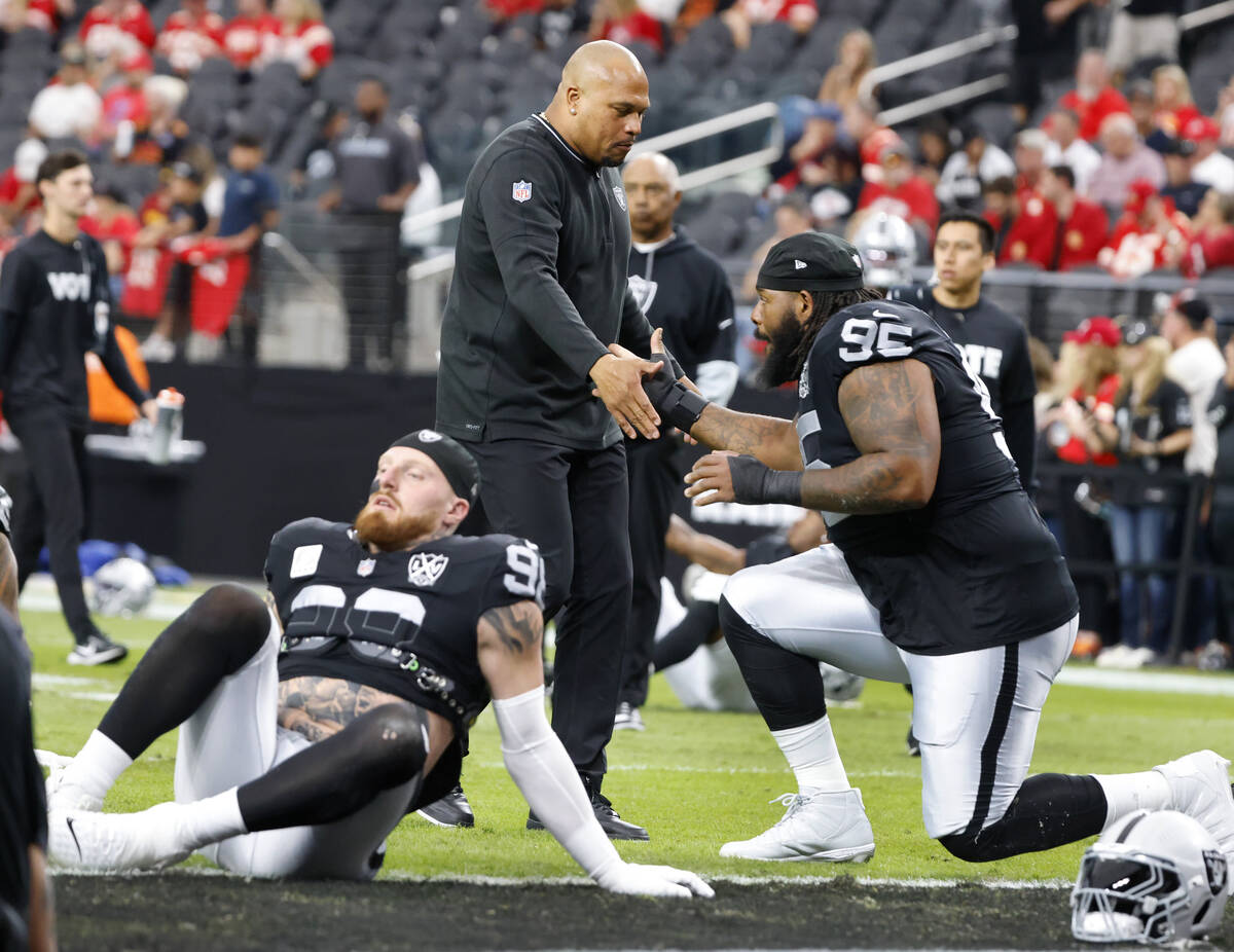 Raiders defensive end Maxx Crosby (98) stretches as head coach Antonio Pierce greets defensive ...