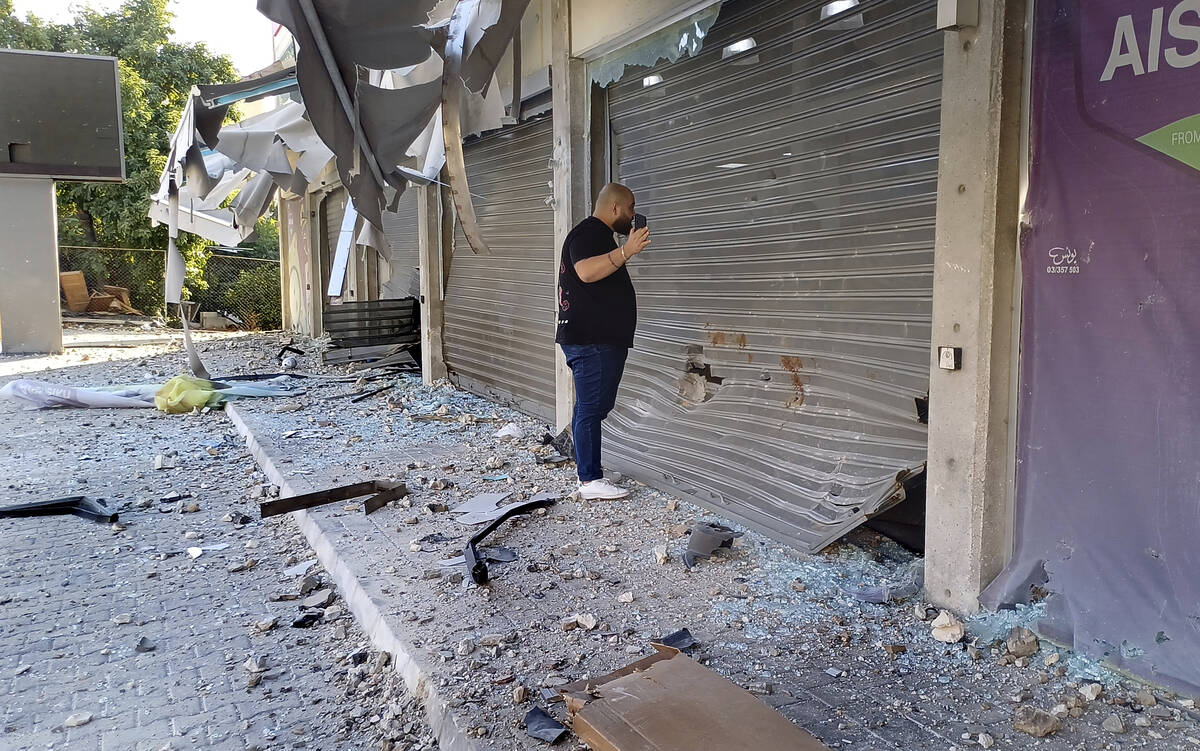 A man checks damaged shops at the site of an Israeli airstrike that hit a building, in the sout ...