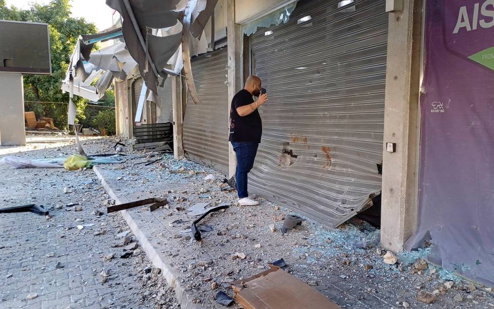 A man checks damaged shops at the site of an Israeli airstrike that hit a building, in the sout ...